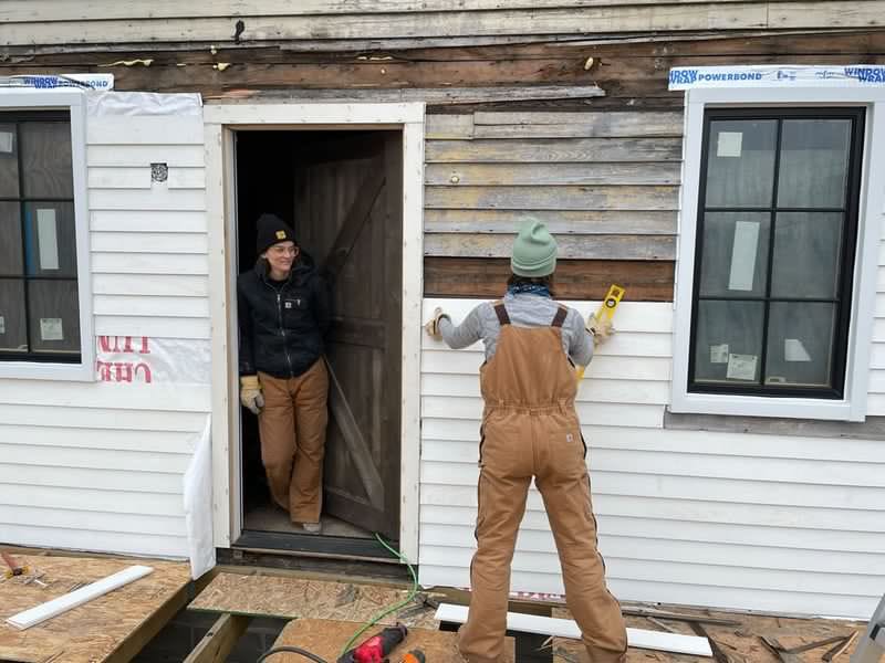 Skilled trades worker homeowner standing in front of a house