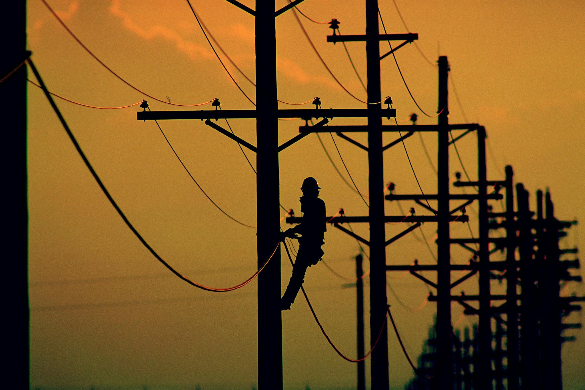 Lineman working near power lines at dusk